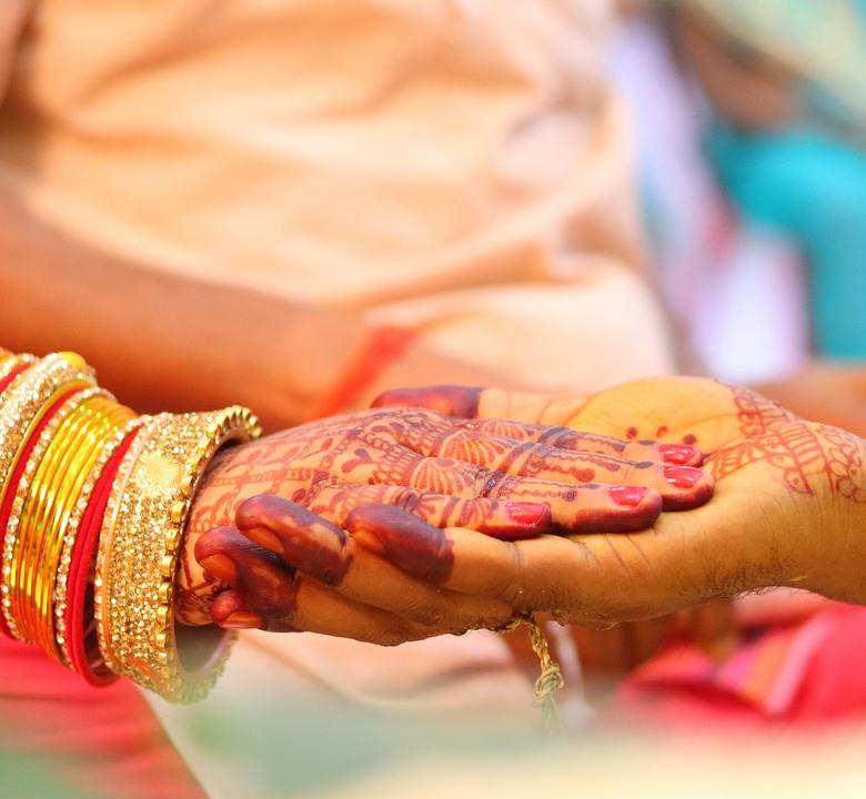 Hennaed hands held in the groom's palm